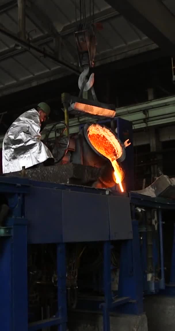 Κατακόρυφο βίντεο για τηλέφωνα και tablet. Λιώσιμο πορτοκαλί μετάλλου σε μεταλλουργικό εργοστάσιο. Υγρός σίδηρος από την κουτάλα — Αρχείο Βίντεο