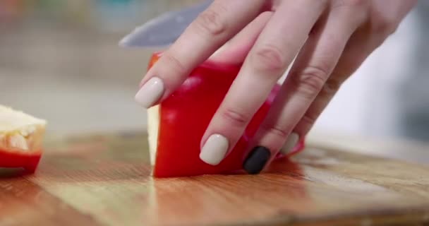 El primer plano de una mujer que corta un pepino fresco en una tabla de corte de madera, en el fondo son las verduras - tomates, pimientos, col, lechuga, cebollas verdes. Movimiento lento . — Vídeos de Stock