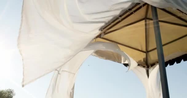 Gazebo op het strand aan zee. Zandstrand. Gordijnen ontwikkelen zich in de wind. — Stockvideo