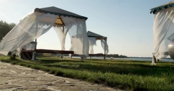 Gazebo en la playa junto al mar. Playa de arena. Las cortinas se desarrollan en el viento . — Vídeo de stock