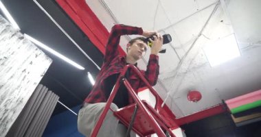 Genç yakışıklı profesyonel fotoğrafçı stüdyoda bir modelin fotoğrafını çekiyor. Ele geçirilen resimlerden memnun. Dijital kamera DSLR.