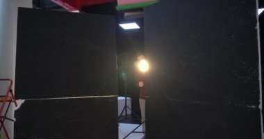 Genç yakışıklı profesyonel fotoğrafçı stüdyoda bir modelin fotoğrafını çekiyor. Ele geçirilen resimlerden memnun. Dijital kamera DSLR.
