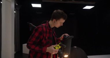 Genç yakışıklı profesyonel fotoğrafçı stüdyoda bir modelin fotoğrafını çekiyor. Ele geçirilen resimlerden memnun. Dijital kamera DSLR.