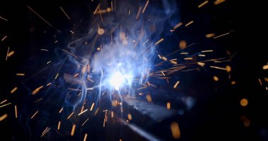 Üretim fabrikasındaki yarı otomatik kaynak makinesinde elektrot ile çalışan kaynakçı. elektrot kaynak yapan metal kıvılcımlar