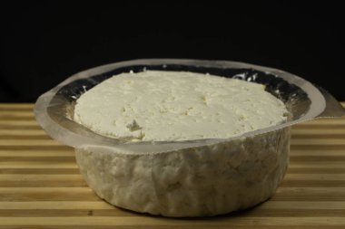 Pakette yumuşak peynir var. Siyah bir arkaplanda
