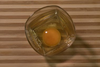 Cam bir şişede çiğ yumurta. Siyah bir arka planda. Masanın üzerinde.