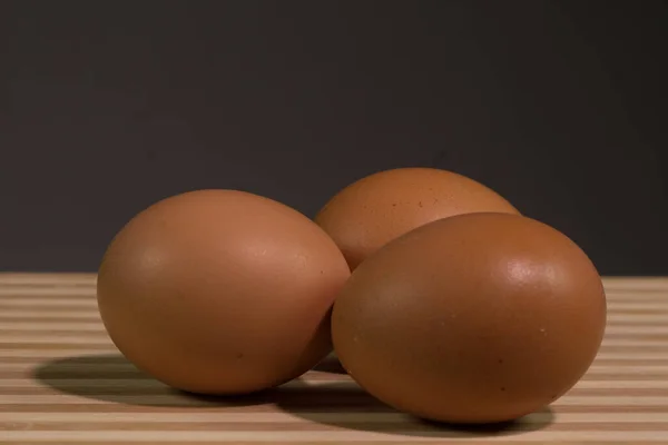 Tres Huevos Pollo Marrón Fondo Negro Cerca Una Tabla Madera — Foto de Stock