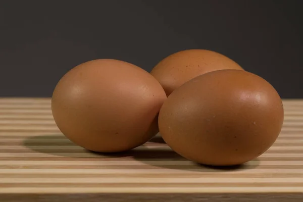 Drie Bruine Kippeneieren Zwarte Achtergrond Van Dichtbij Een Houten Plank — Stockfoto