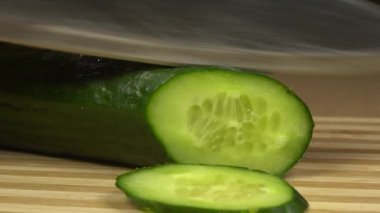 Erkek eli kesme tahtasında salatalık kesiyor. Mutfakta ya da restoranda salata hazırlayan tanınmayan genç beyaz adamın yakın çekimi. Sağlıklı beslenme, vejetaryen yemeği, yaşam tarzı..