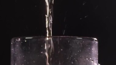 Barmen bardağa köpüklü bira dolduruyor. Karanlık bir arka planda. Kameranın üst görüntüsü, bira köpüğü.