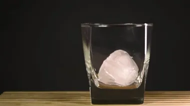 Macro vuruldu. Barmen, barda ayna masasındaki müşterilere alkollü kokteyl hazırlarken bardağa kristal buz koyuyor..