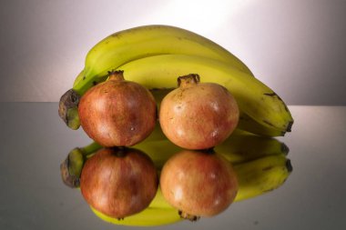 Sarı muzlar ve aynalama masasında kırmızı nar. Kopyalama alanı olan Gorizontal resim.