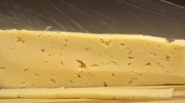 Erkek aşçının ya da ev kadınının peyniri bıçakla keserken yakın çekimi..