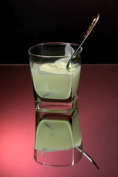 Grecki Jogurt Szklanym Słoiku Łyżką Czerwonym Czarnym Tle Blisko Odbicie — Zdjęcie stockowe