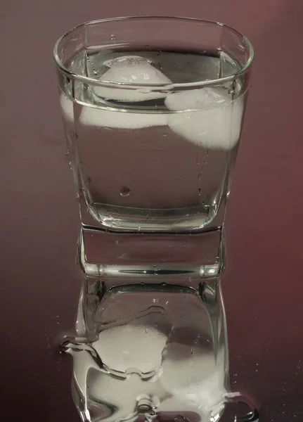 黒の背景に氷のキューブと2ショットグラスにボトルから冷凍ウォッカを注ぐバーテンダー バーマンは 透明なアルコール飲料ラムテキラをショットガラスに注ぎます 鏡面反射 ブルゴーニュの背景 — ストック写真
