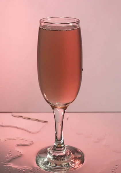 Glasses with red wine. Mirror reflection, pink background