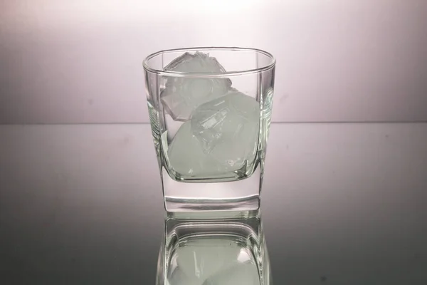 Aynada buz küplü bir bardak viski. Kopya uzayı ile yatay görüntü. Gri arkaplan