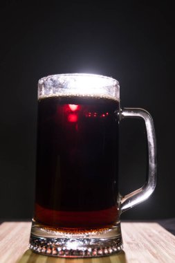 Kopyalama alanı olan tahta arka planda cam bira. Karanlık bir arka planda.