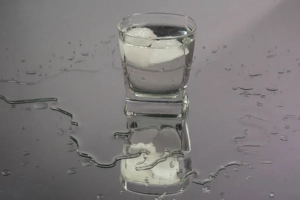Barmen, siyah arka planda buz küpleri olan iki kadehe şişeden dondurulmuş votka dolduruyor. Barmen şeffaf alkolden doldurur shot bardağında rom tekila içer. Ayna yansıması, bordo arkaplan