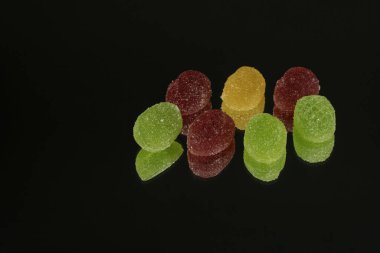 Birkaç marmelat şekeri siyah bir aynada izole edilmiş.