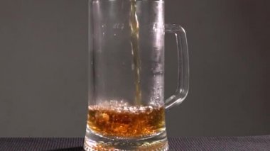 Barmen bardağa köpüklü bira dolduruyor. Karanlık bir arka planda