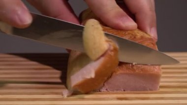 Keskin bıçakla domuz pastırması doğrayan tanınmamış bir erkek aşçıya yakın çekim.