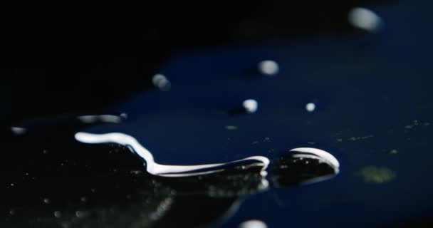 黒い背景にアニメーション流体 表面の水の動き 透明な大きな青と紫の滴がゆっくりと黒い背景に表示されます — ストック動画