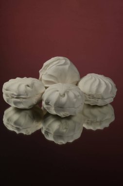 Kırmızı ayna arka planında üç beyaz lokum.