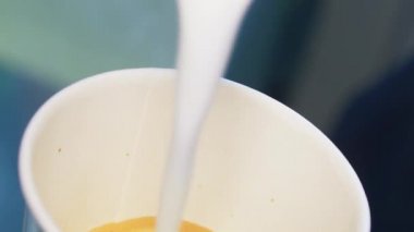 Espresso makinesinden sütlü kahve fincanına taze kahve ekliyorum.