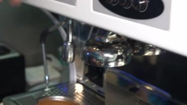 Espresso makinesinden sütlü kahve fincanına taze kahve ekliyorum.