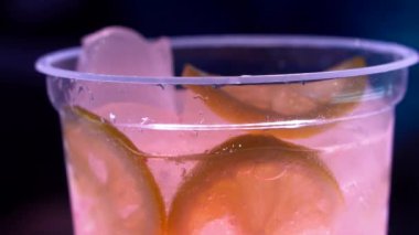 Yavaş çekimde pembe içecek güzel bir şekilde buzlu ve limon dilimli bardağa dökülüyor.
