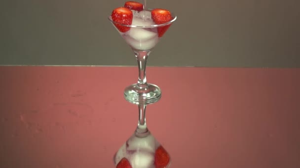 Giet Tequila Glas Ijsblokjes Aardbeien Slow Motion Spiegel Roze Achtergrond — Stockvideo