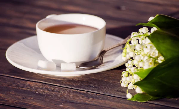 Çiçek bir buket ile beyaz bir fincan sıcak çay 