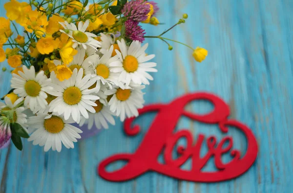 De inscriptie op de houten achtergrond liefde over bloemen — Stockfoto