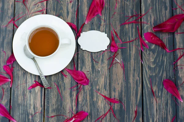 Heißer Tee und Pfingstrosenblüten auf dunklem — Stockfoto