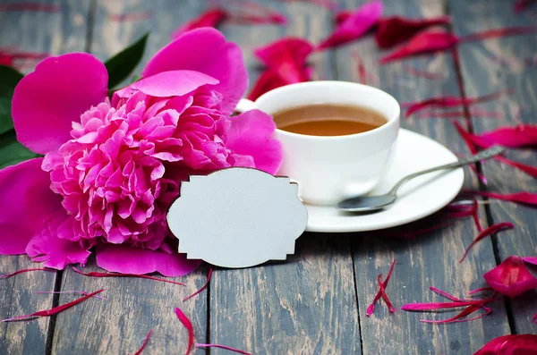 Hot tea and peony petals on dark