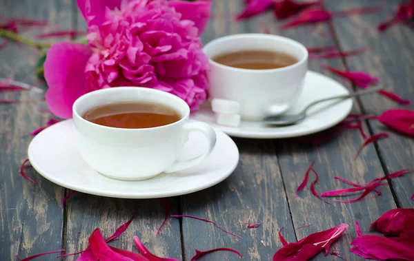 Heißer Tee und Pfingstrosenblüten auf dunklem — Stockfoto