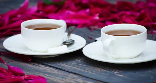 Gorąca herbata i piwonia płatki na ciemny — Zdjęcie stockowe