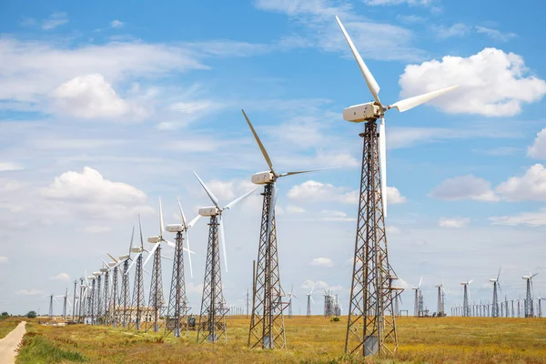 Wind power plant in the field. Wind power station on the horizon, against a beautiful blue sky with clouds. Industry, business card