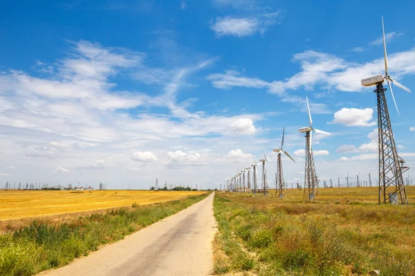 Wind power plant in the field. Wind power station on the horizon, against a beautiful blue sky with clouds. Industry, business card