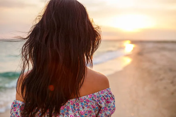 Young woman walk on an empty wild beach towards celestial beams of light falling from the sky, the concept of travel and tourism, leisure at sea