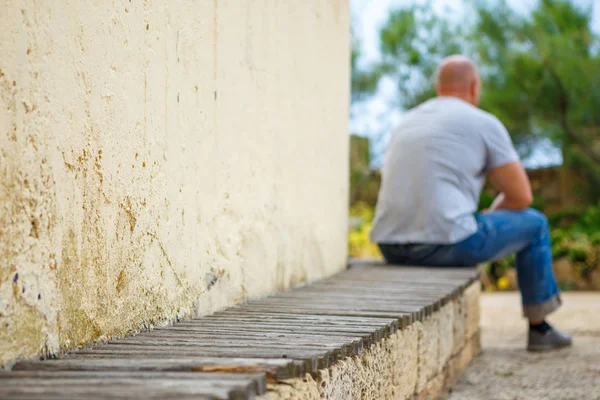 Young man sitting alone on park bench, sad and sad mood.