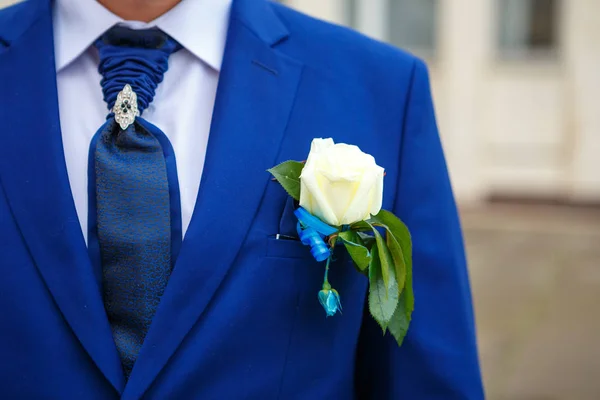 Groom in a suit holding buttonhole. the room with flowers. love and romance