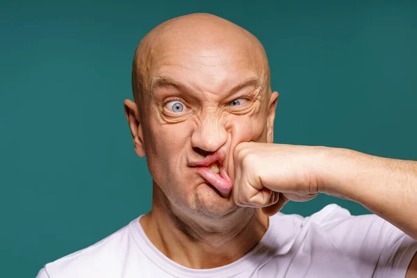 portrait of a bald man punches himself on the cheek, facial expressions