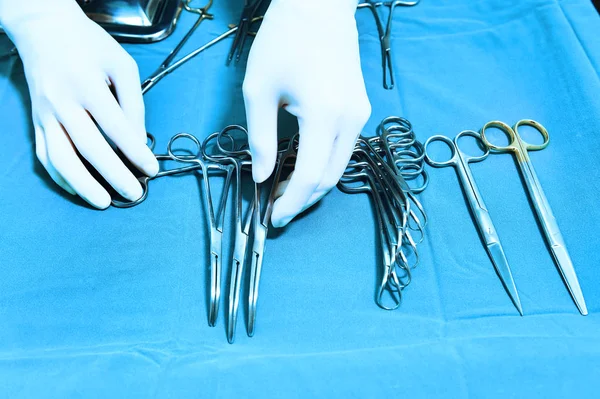 Detalle plano de instrumentos de cirugía esteralizada con una mano agarrando una herramienta —  Fotos de Stock