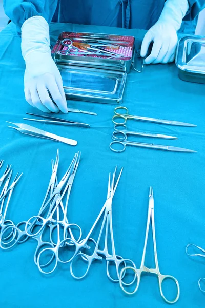 Detalle plano de instrumentos de cirugía esteralizada con una mano agarrando una herramienta —  Fotos de Stock