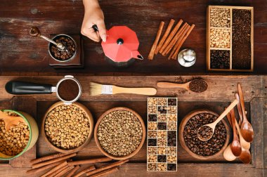 Taze çekilmiş kahve çekirdekleri bir metal filtre ve Kahvenin yanında kırmızı çaydanlık kase.