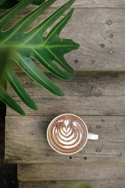 ラテアートの木製の背景にコーヒーのカップ — ストック写真