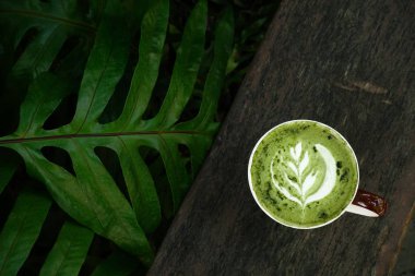 Bir fincan yeşil çay, ahşap arka planda matcha latte.