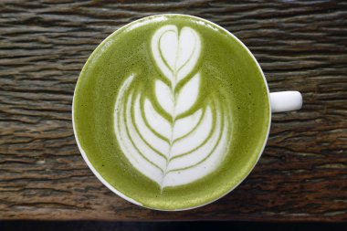 Bir fincan yeşil çay, ahşap arka planda matcha latte.